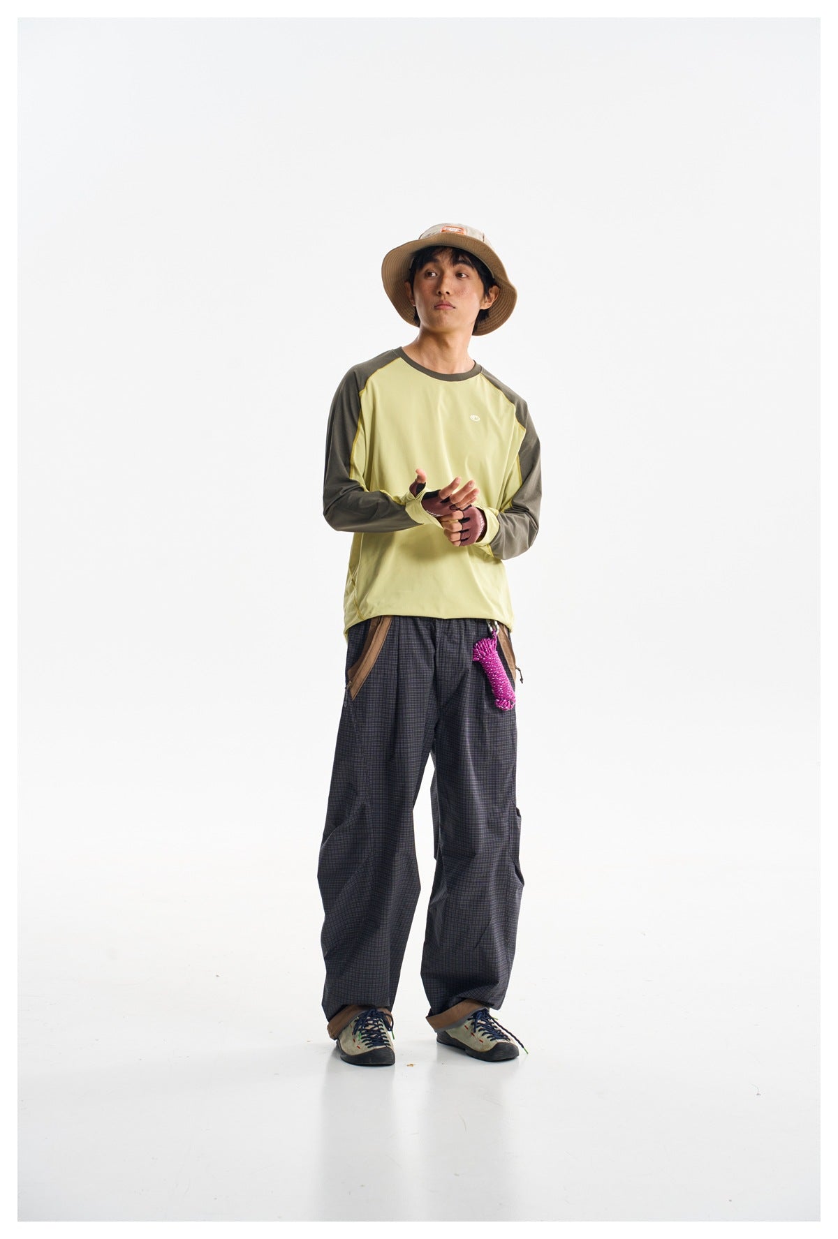 Front view of a model wearing a pale yellow raglan long-sleeve shirt with dark olive sleeves and loose plaid pants.