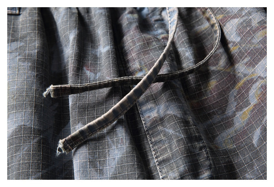 Close-up of a drawstring and pocket opening on dark gray plaid trousers.