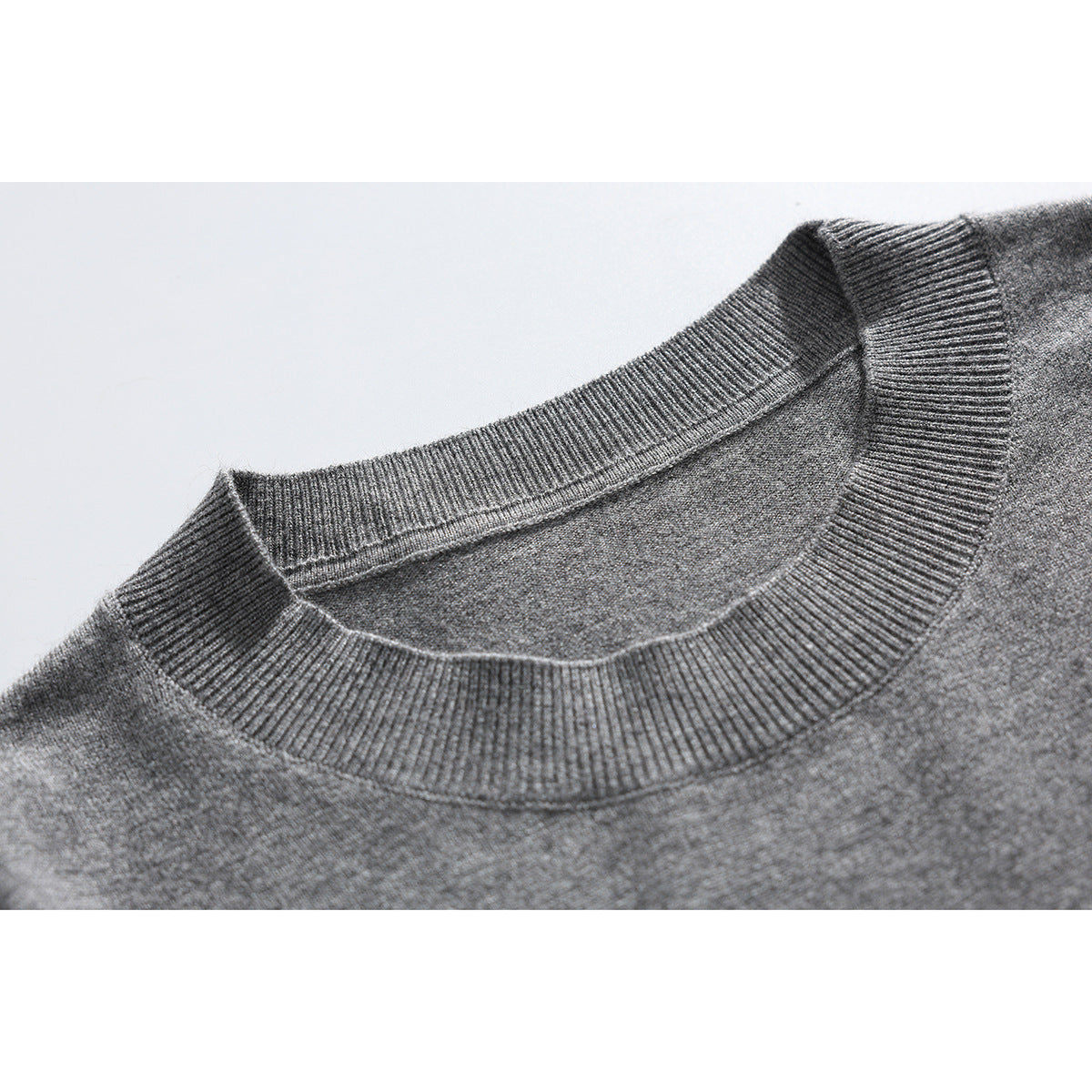 Close-up of the ribbed crew neck and knit texture of a gray short-sleeve sweater.