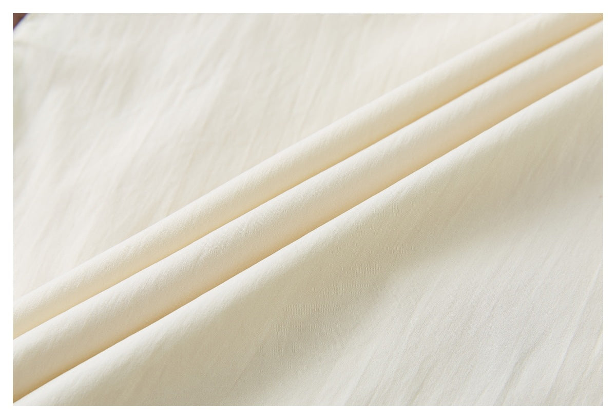Close-up of smooth ivory fabric draped in soft folds.