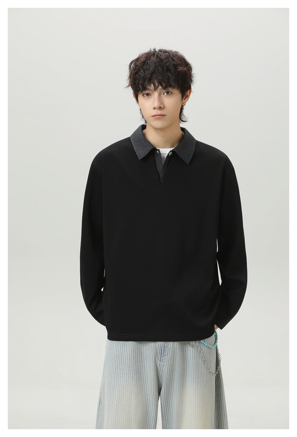 Front view of a model wearing a black long-sleeve top with a charcoal pointed collar and V-shaped placket.