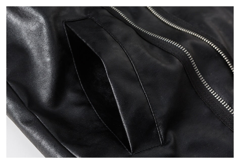 Close-up of a black jacket's angled welt pocket beside silver zipper teeth.
