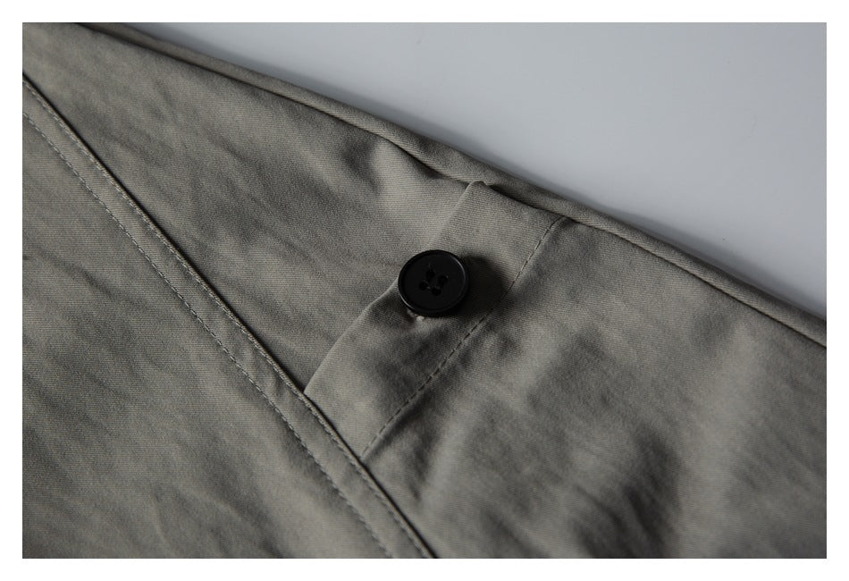 Close-up of gray shorts showing a black button fastening and stitched fly.
