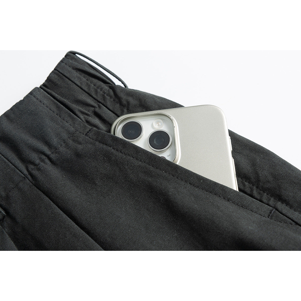 Close-up of a deep charcoal trouser pocket holding a smartphone.