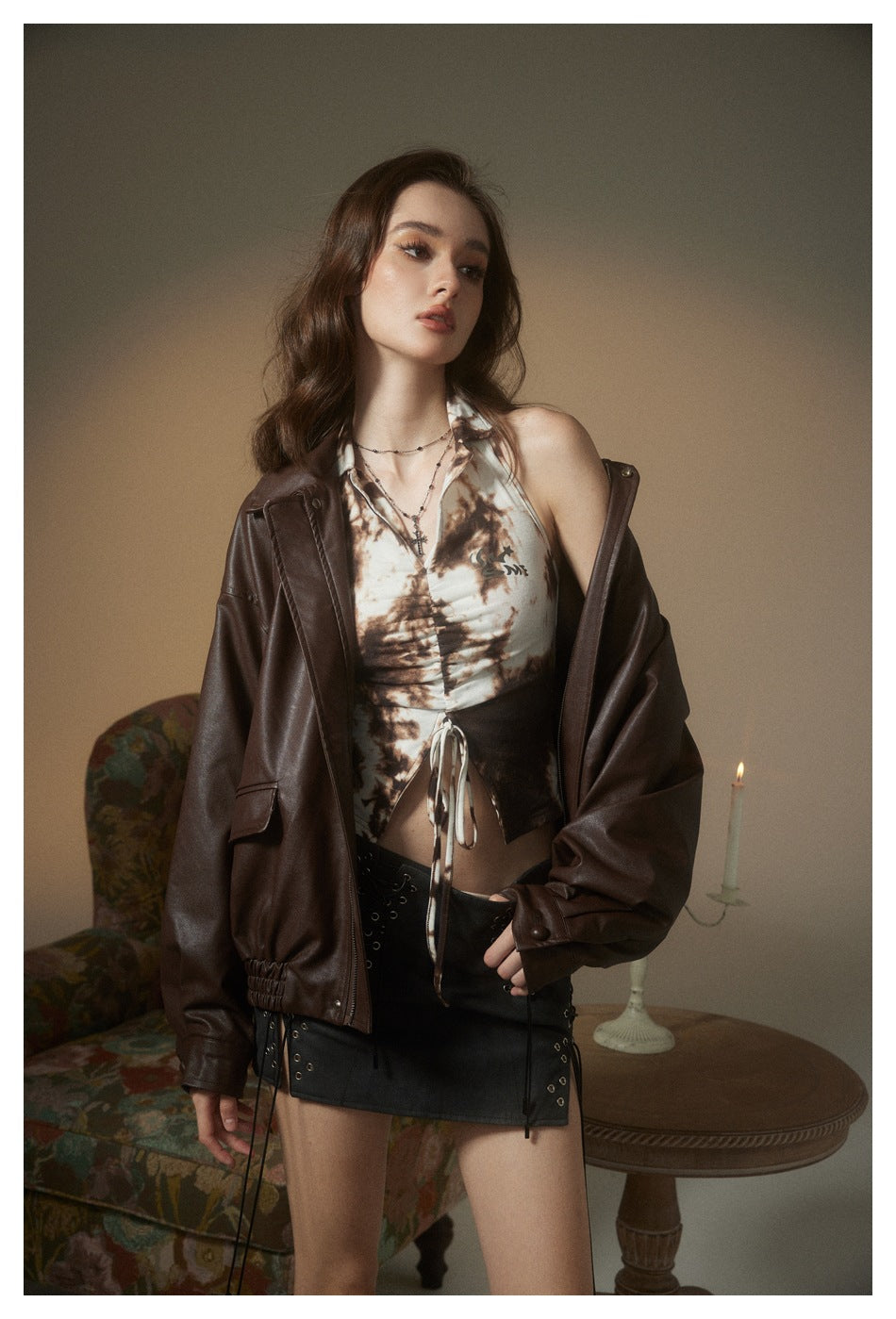 Model wearing an open dark brown jacket over a cream-and-brown printed halter top and black mini skirt.