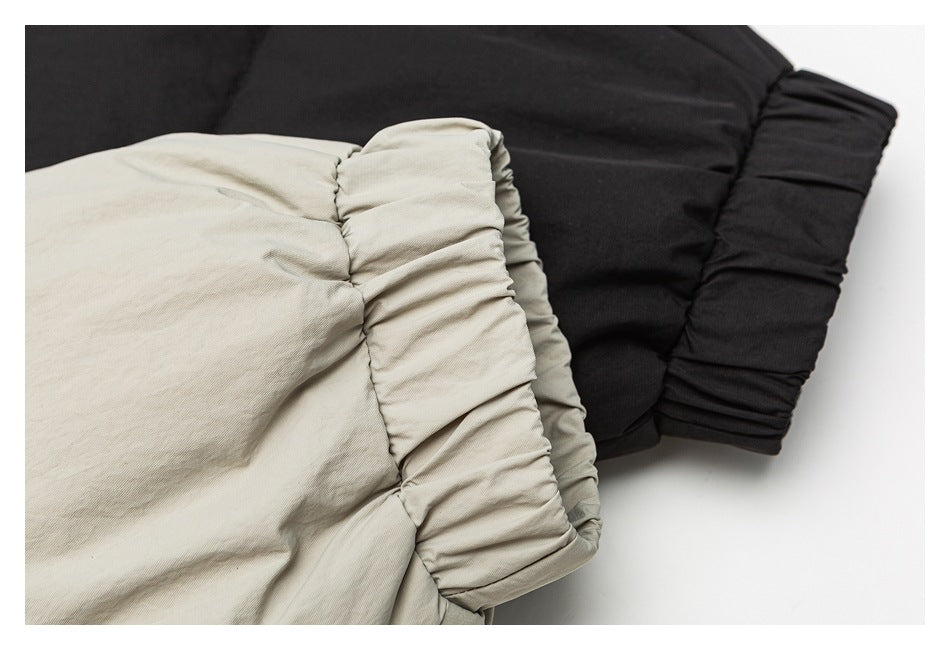 Close-up of beige and black jacket cuffs with gathered, layered fabric.