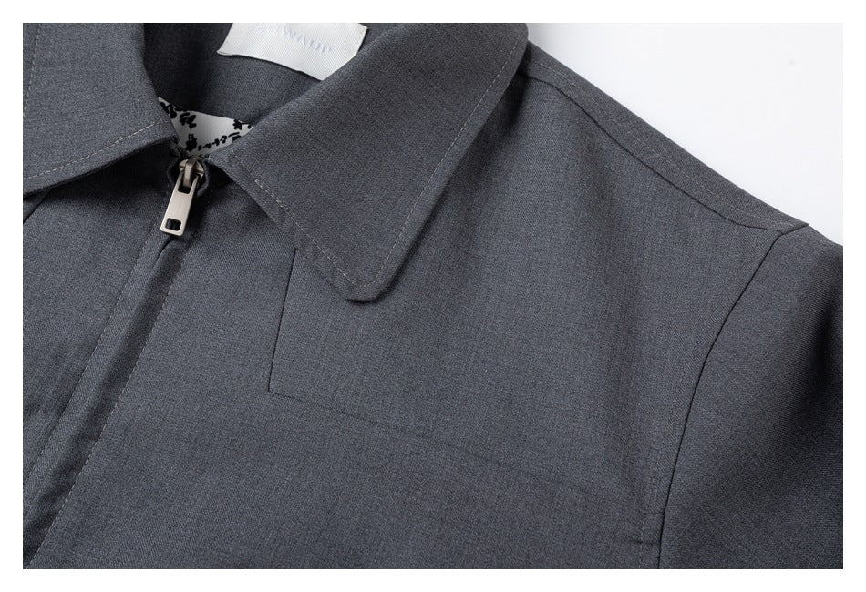 Close-up of the gray jacket's pointed collar, zipper, shoulder seam, and chest stitching.