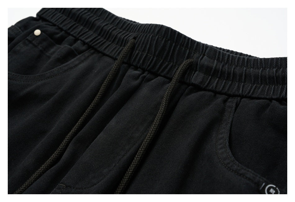 Close-up of the black pants elastic waistband, drawstrings, and front pocket stitching.