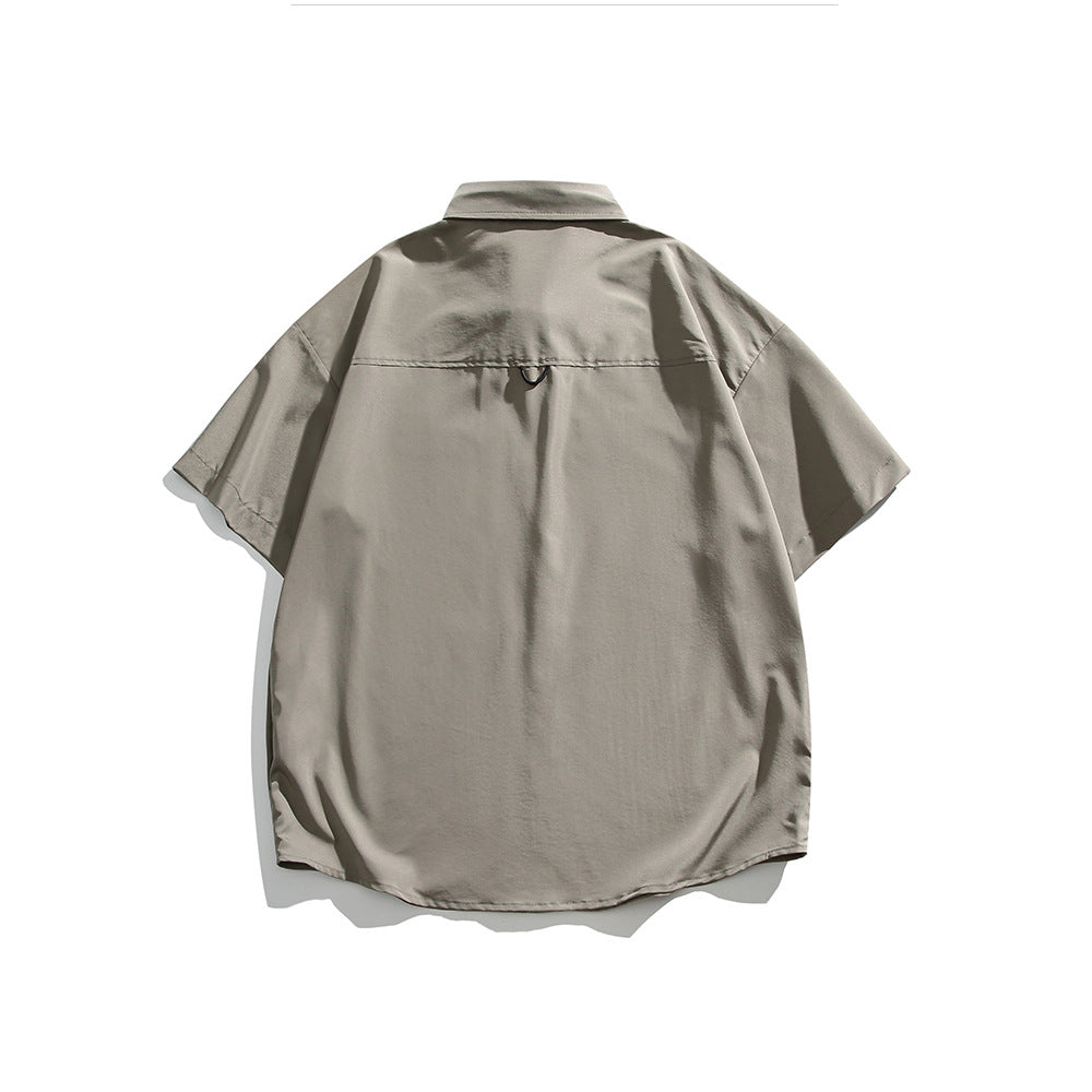 Back view of a taupe short-sleeve collared shirt laid flat, with a small loop below the yoke.