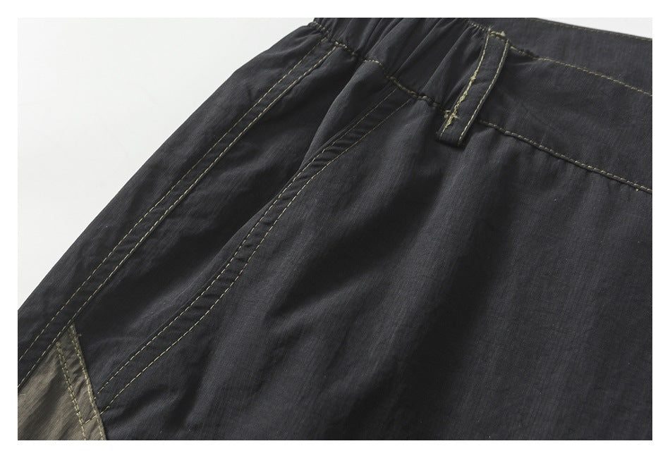 Close-up of the charcoal shorts' elastic waistband, belt loop, and stitched side seam.