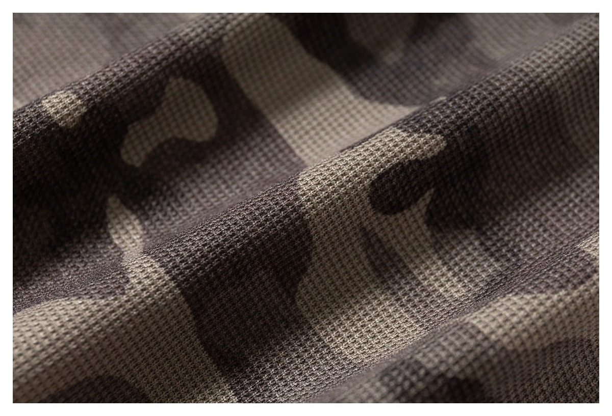 Macro view of the textured weave and folds in gray-brown camouflage fabric.