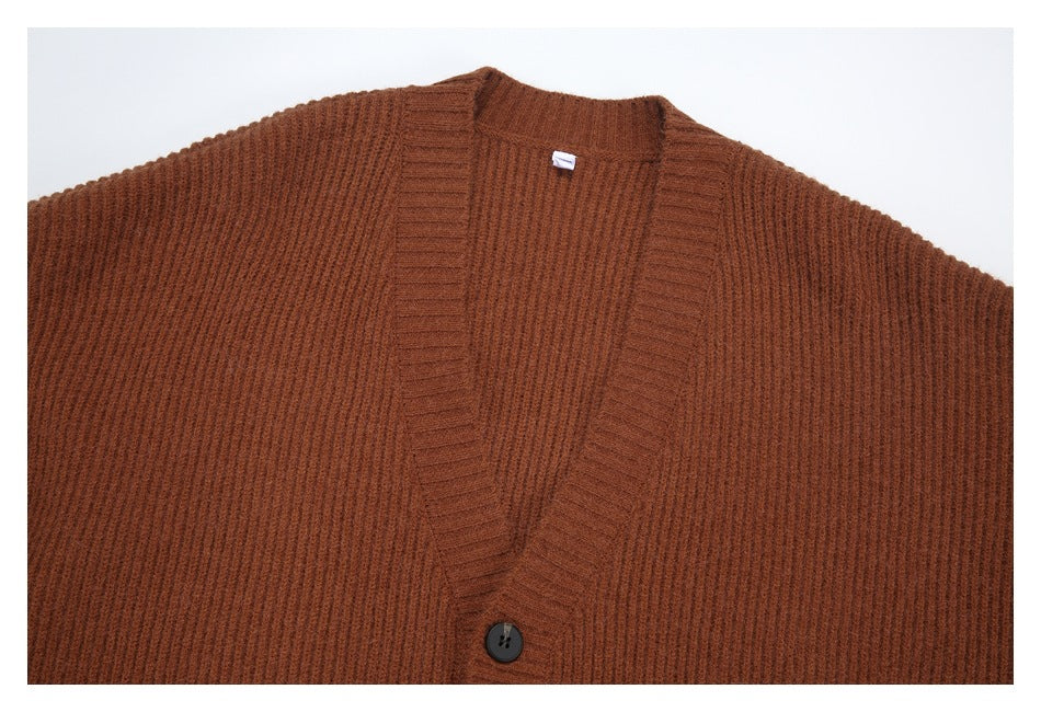 Close view of a rust-brown ribbed cardigan's V-neck, front bands and dark button.