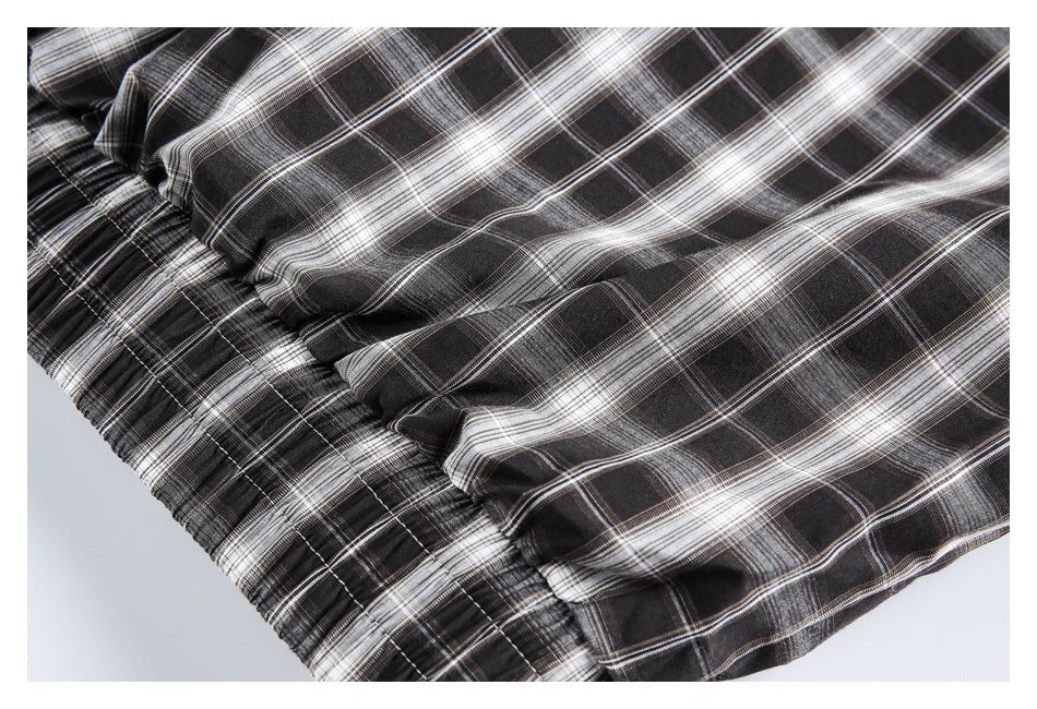 Close-up of black, gray, and white plaid fabric gathered along a stitched seam.