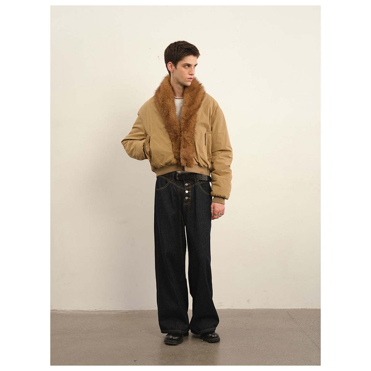 Model wearing a tan bomber jacket with a wide brown plush collar and black wide-leg jeans, full-length view.