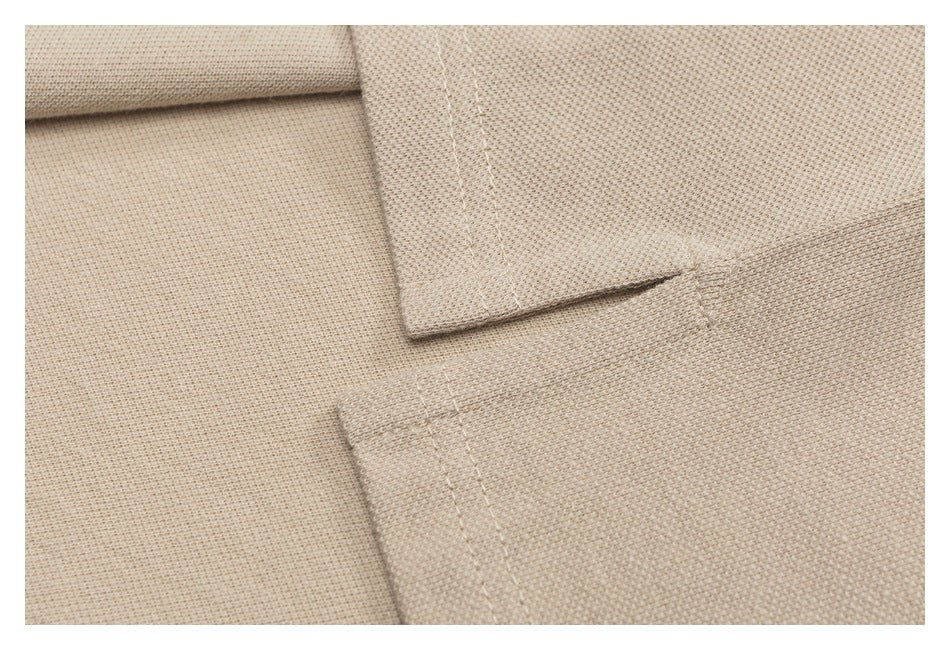 Close-up of beige polo fabric with overlapping stitched garment edges.