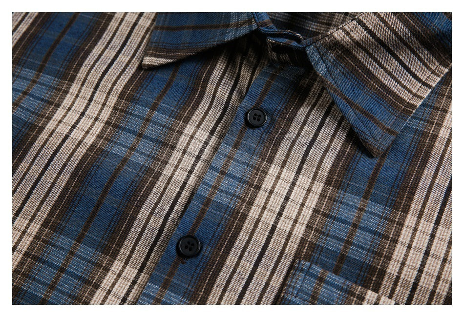 Close-up of the plaid shirt's black buttons, front placket and chest pocket edge.