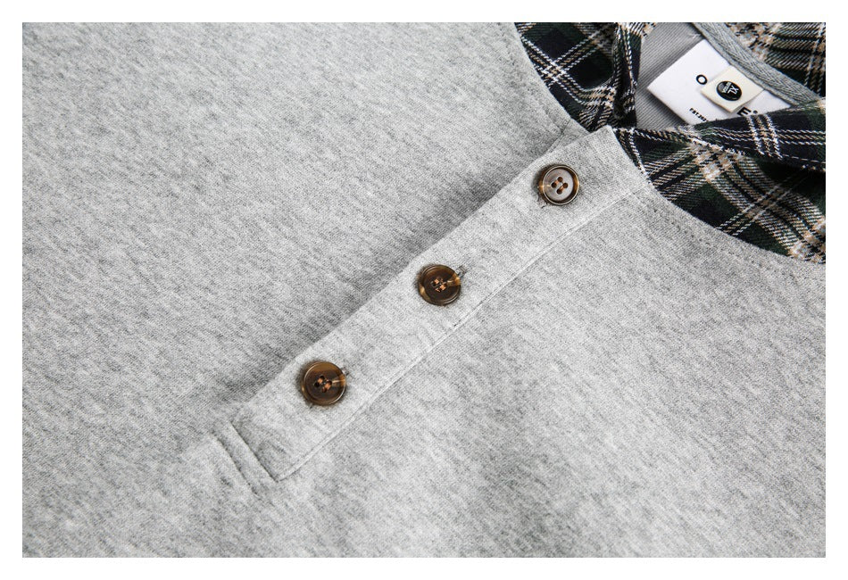 Close-up of a gray top's three-button placket and plaid neckline.