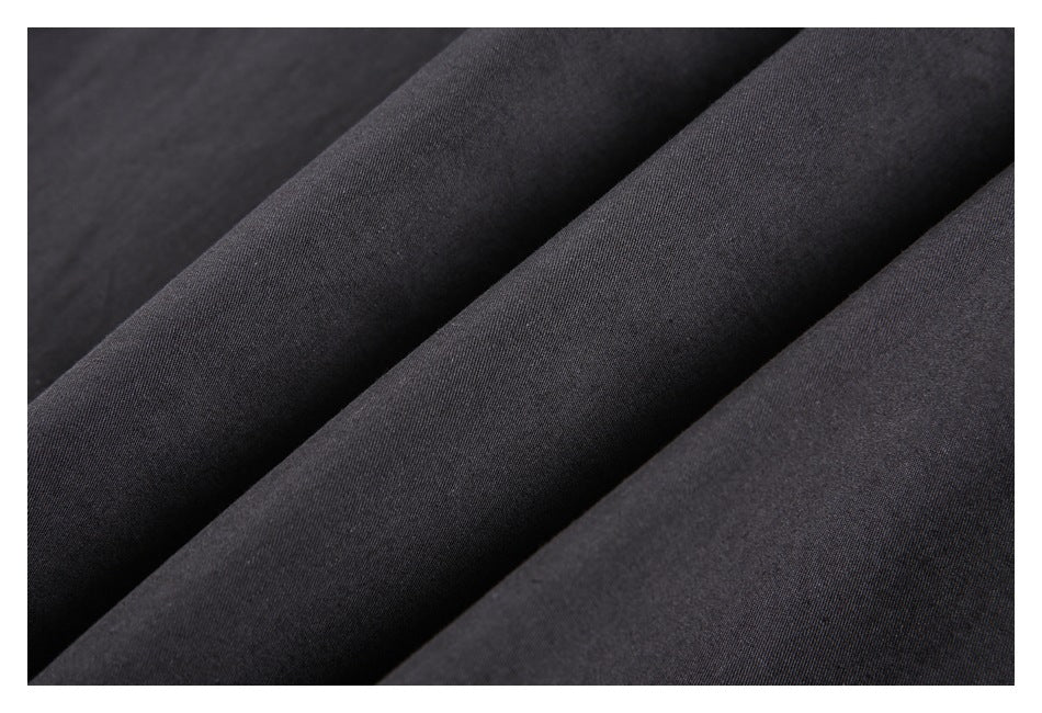 Close-up of dark charcoal fabric arranged in soft diagonal folds, showing its fine surface texture.