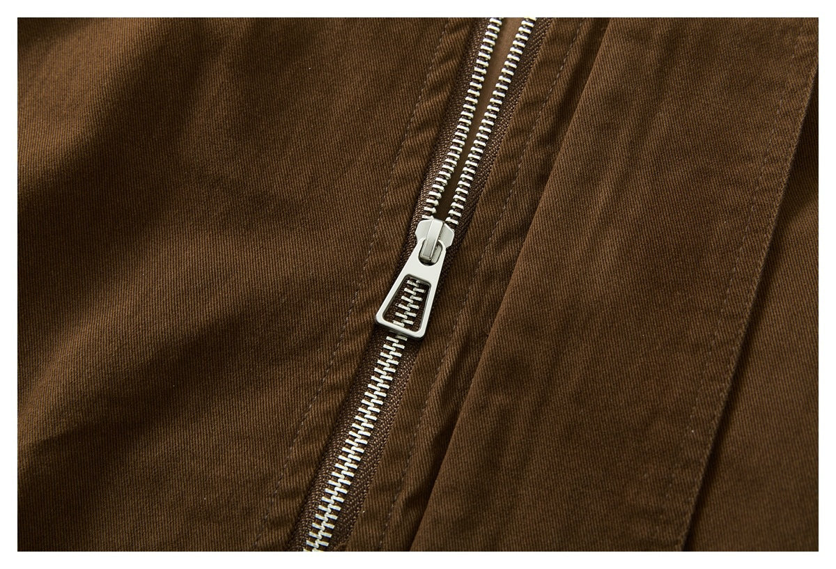 Close-up of the dark brown jacket's silver front zipper and surrounding stitched fabric.