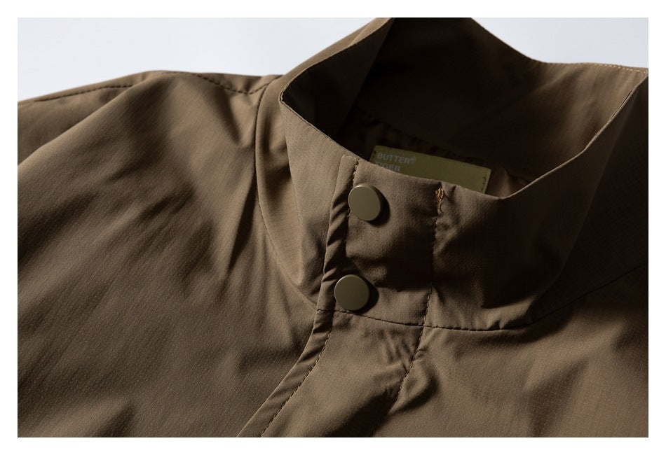 Close-up of a brown jacket's tall collar and front placket with two round buttons.