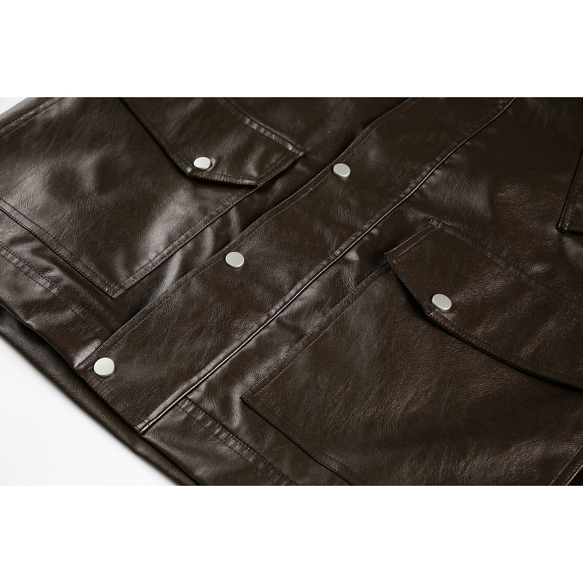 Close-up of a dark brown jacket front with flap pockets and silver snap buttons.