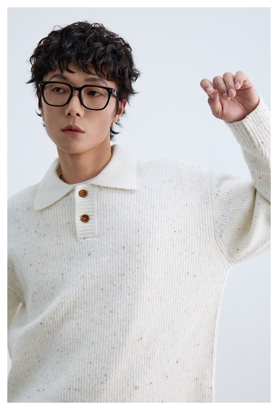 Close-up of the ivory flecked knit polo sweater, showing its ribbed texture, collar, and two-button placket.