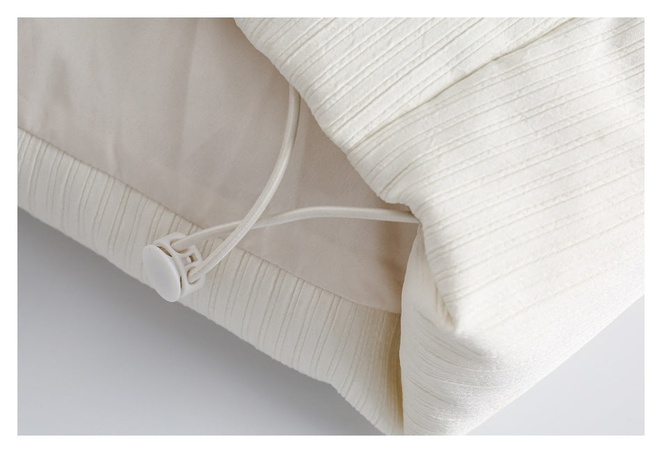 Close-up of an ivory ribbed garment hem with a white drawcord and plastic stopper.