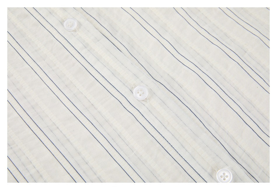 Close-up of an ivory shirt front with thin navy stripes and three white buttons.