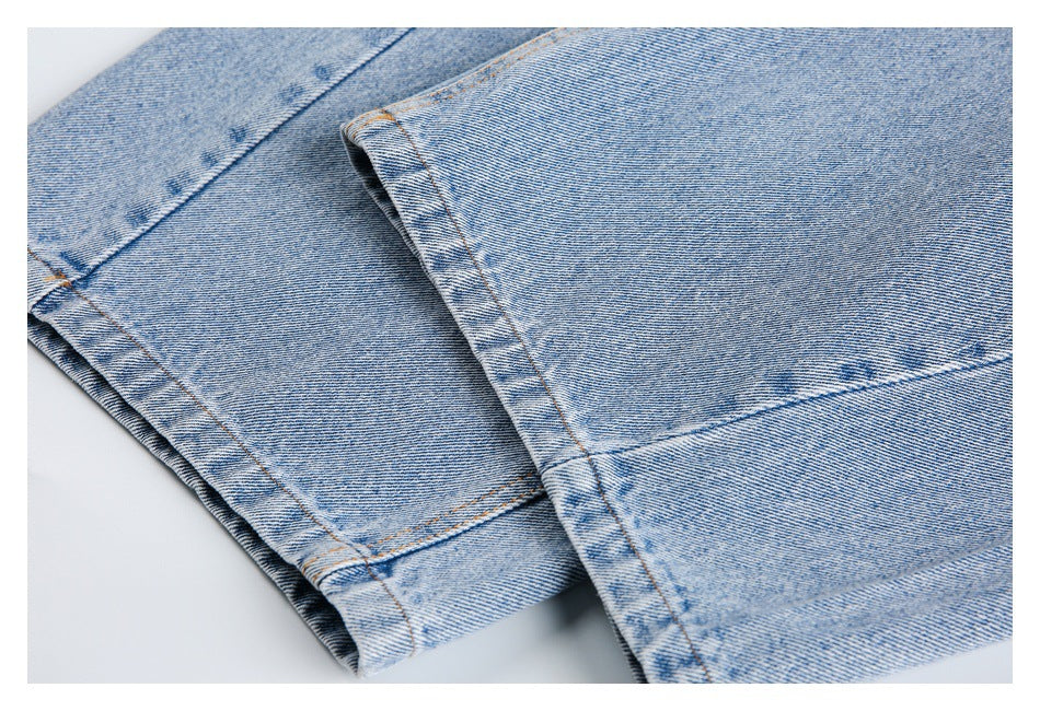 Close-up of light blue jeans folded to show stitched leg hems.