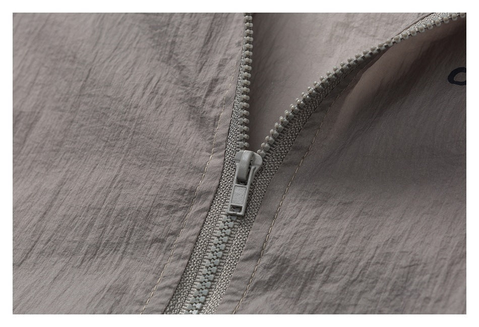 Close-up of a gray zipper and stitching on crinkled gray fabric.