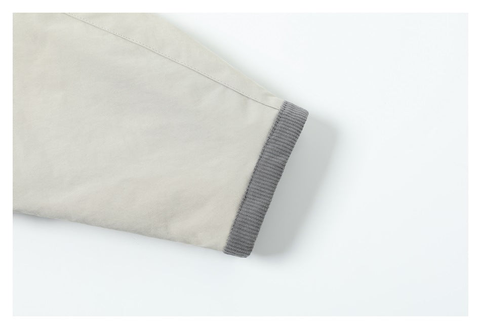Close-up of a cream coat sleeve ending in a gray ribbed cuff.
