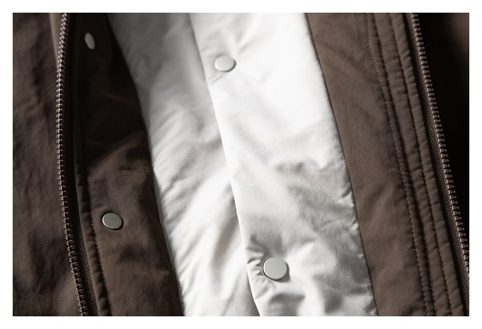 Close-up of a brown jacket opening with a white lining, zipper teeth, and metal snap fasteners.