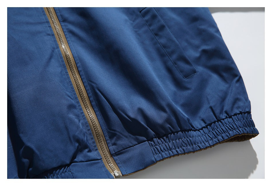 Close-up of the navy jacket's slanted pocket, brown zipper, and gathered elastic hem.