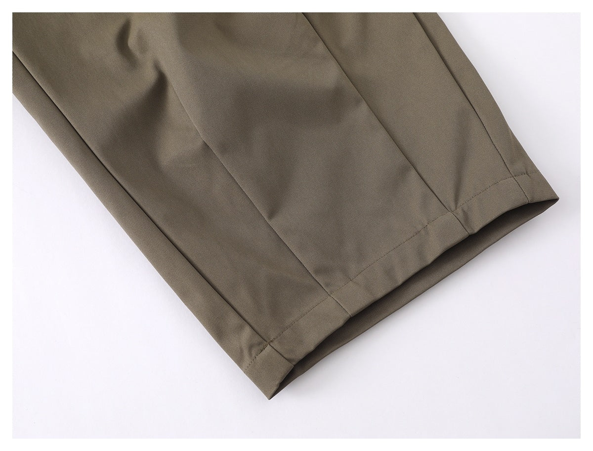 Close-up of the hem and stitched seam on an olive-taupe trouser leg.