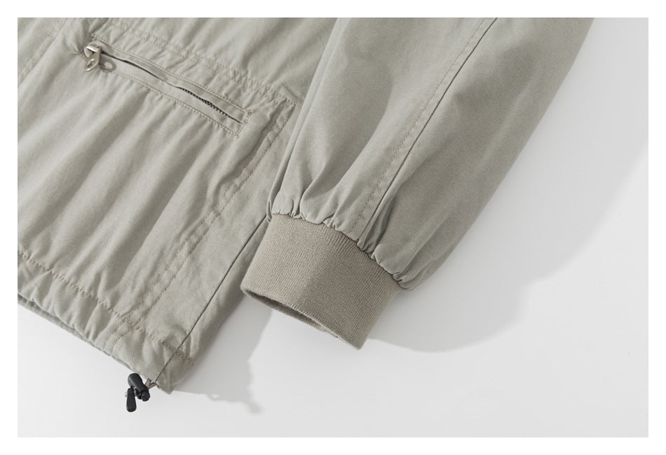 Close-up of a light khaki jacket sleeve with a gathered cuff and ribbed knit wrist; part of a zip pocket is visible.