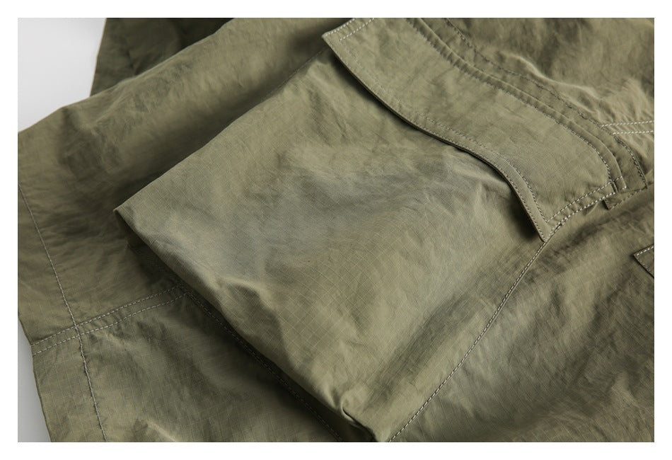 Close-up of olive shorts with a large stitched pocket flap and ripstop fabric.