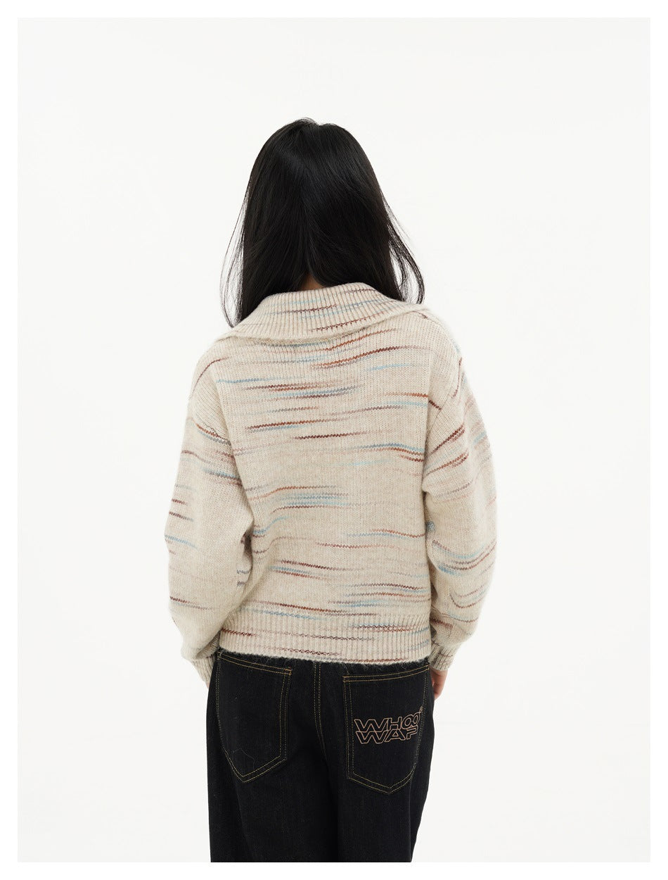 Rear view of a model wearing a cream knit sweater with thin multicolor stripes and dark jeans.