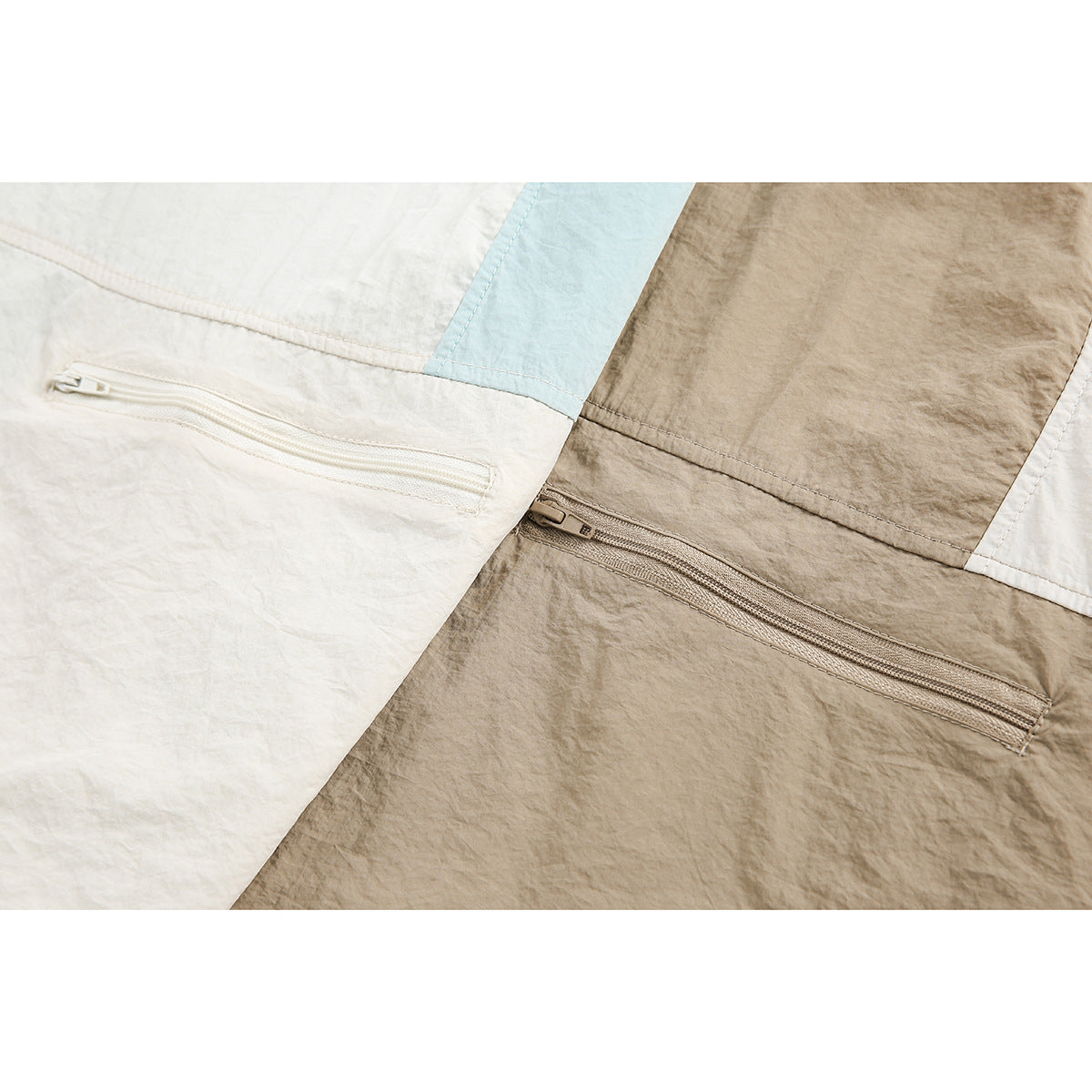 Close-up of ivory and taupe color-block jacket panels with horizontal zip pockets.