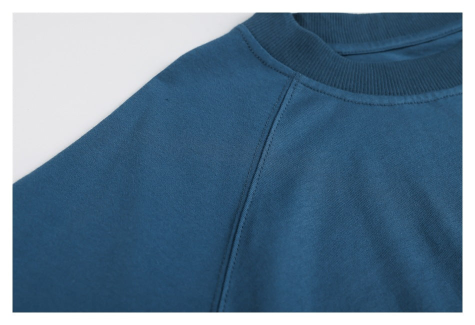 Close-up showing the blue sweatshirt's raglan shoulder seam and ribbed crew neckline.