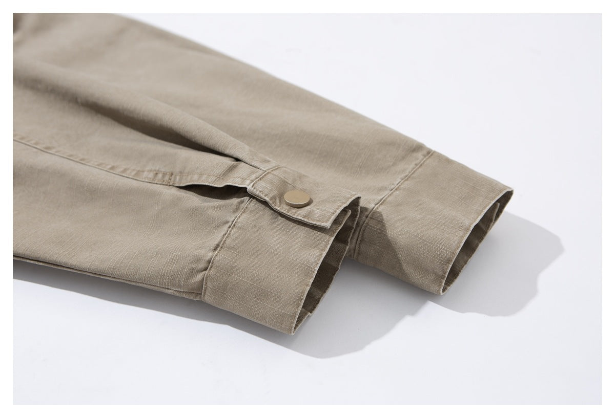 Close-up of the taupe jacket's sleeve cuff with a round snap button and adjustable tab.