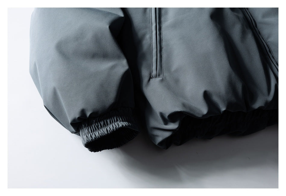 Close-up of a slate-gray jacket sleeve with an elastic cuff and part of the front zipper.