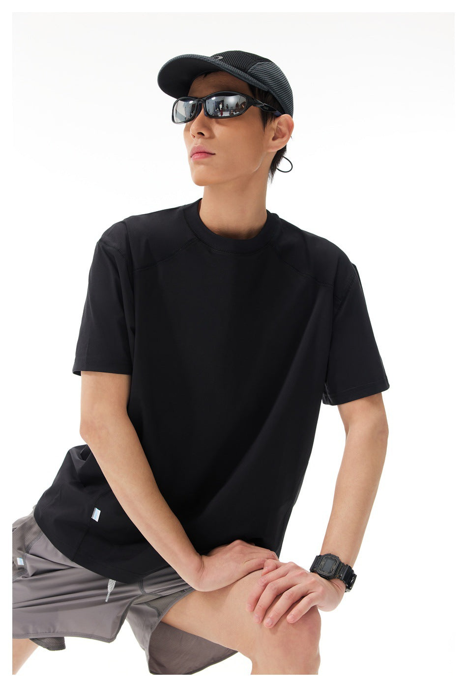 Closer view of a model wearing a plain black short-sleeve shirt with gray shorts.