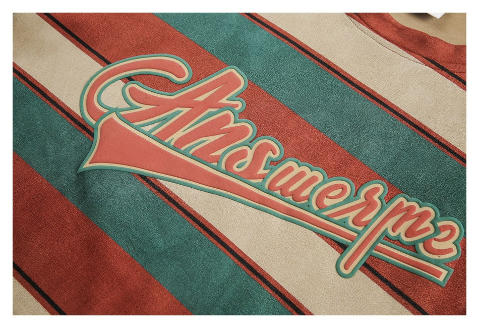 Close-up of a coral script graphic on a beige, teal, and rust striped garment.