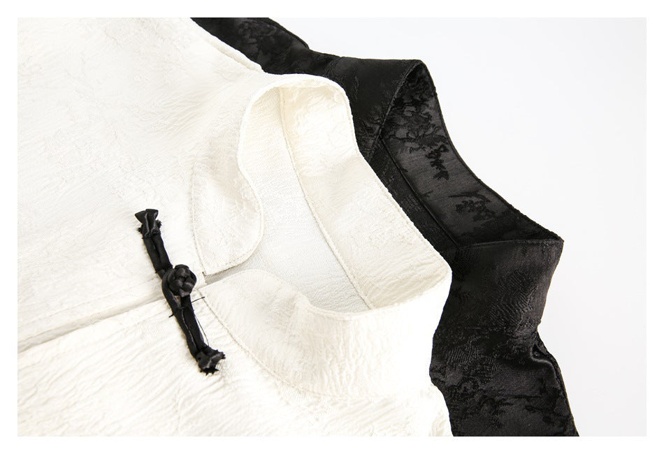 Close-up of ivory and black tops showing their collars, textured fabric, and knotted front closures.