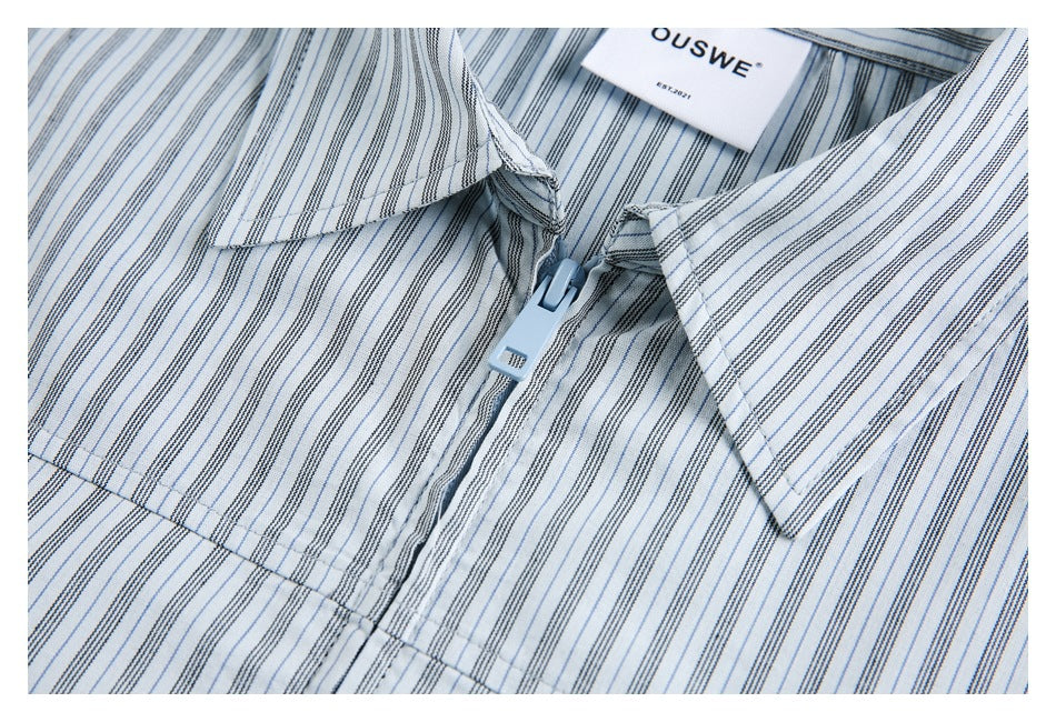 Close-up of a blue-gray striped shirt's pointed collar and light-blue zipper closure.