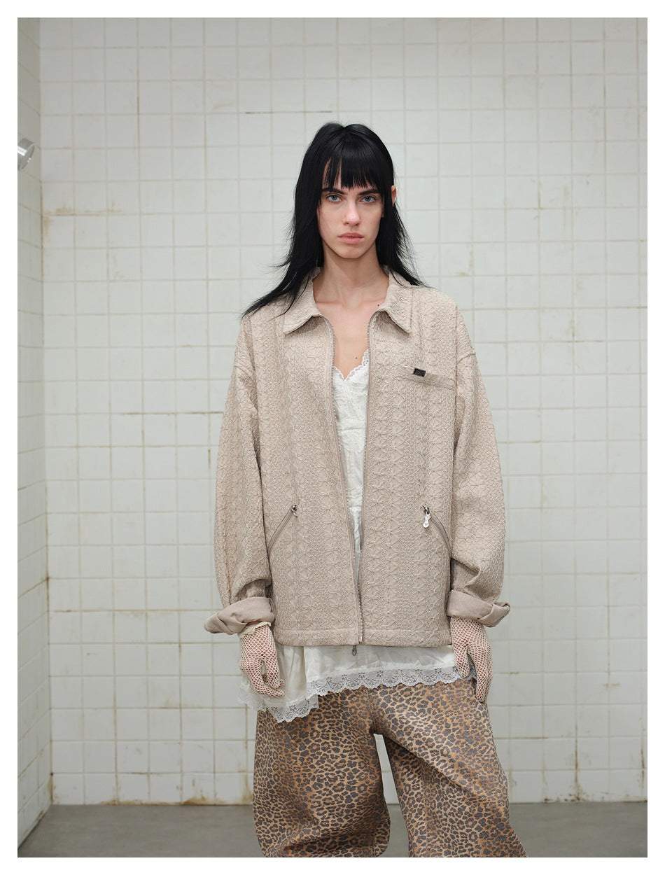 Front view of a model wearing a light beige textured zip jacket over a white lace top with leopard-print pants.