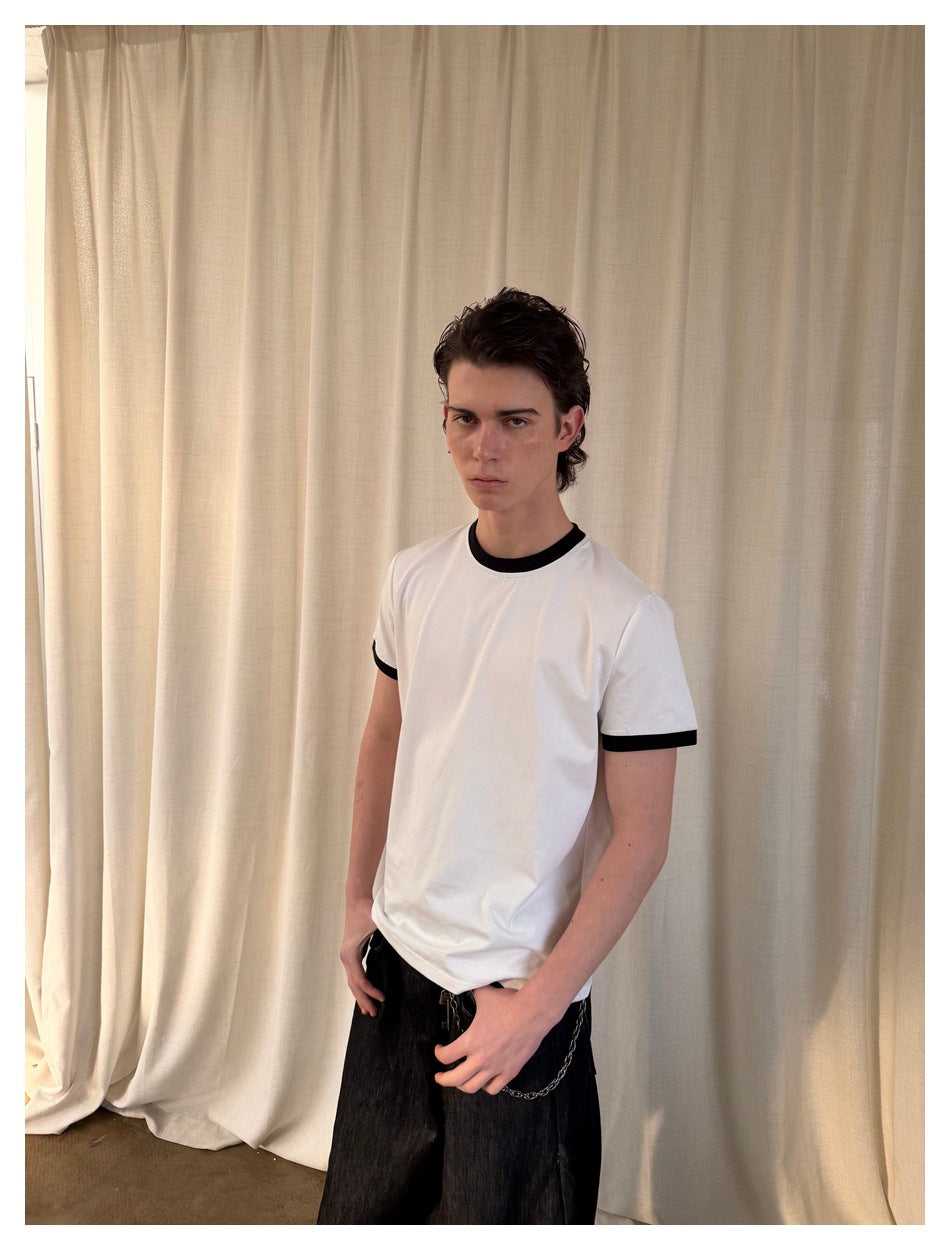 Model wearing a white short-sleeve T-shirt with black contrast trim, shown at a slight angle.