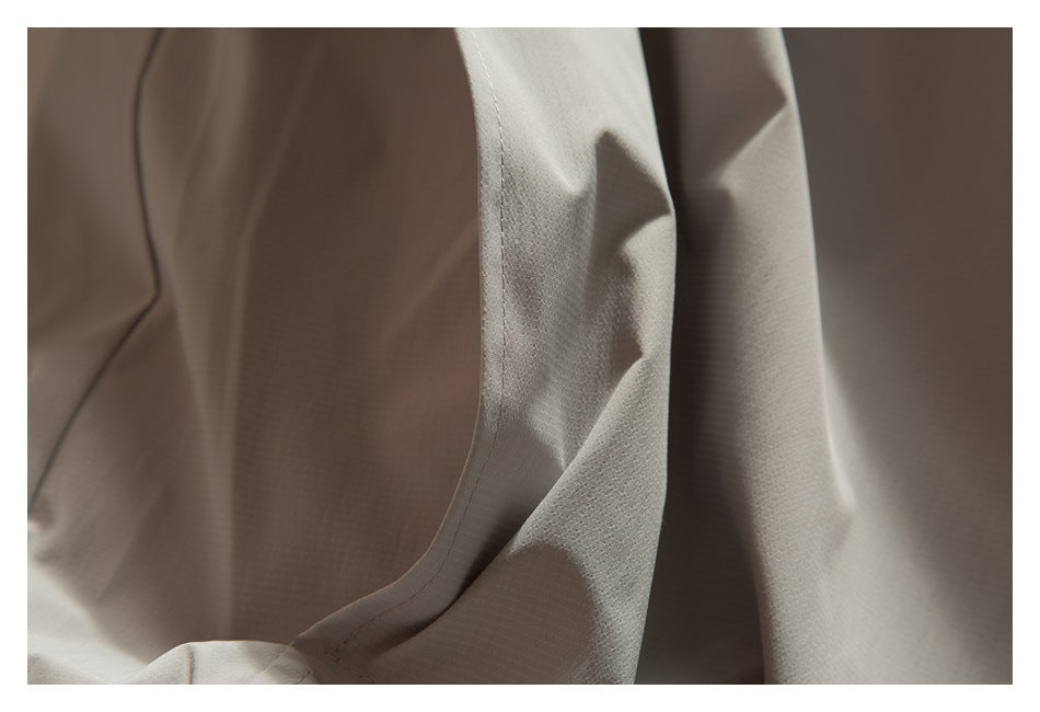 Curved stitched seam on light taupe fabric, shown in a close-up.
