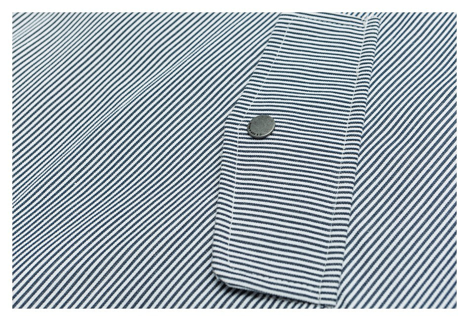 Close-up of a striped jacket pocket flap with a dark snap button.