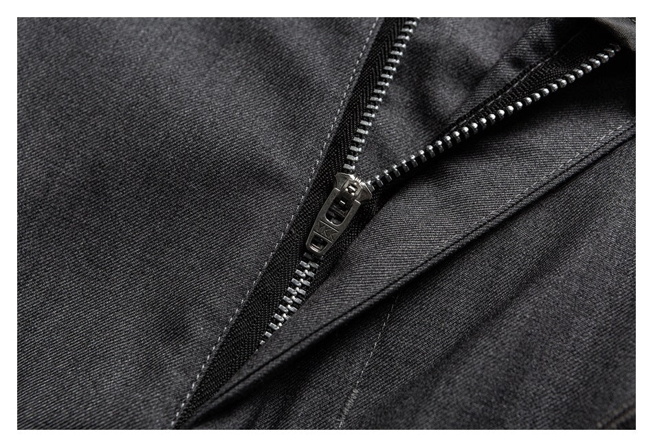 Close-up of a metal zipper and stitching on charcoal gray trouser fabric.